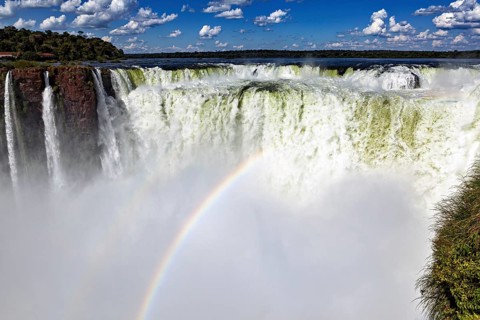Majestic waterfall with rainbow and spray under a cloudy sky, The Iguazu Falls between Argentina