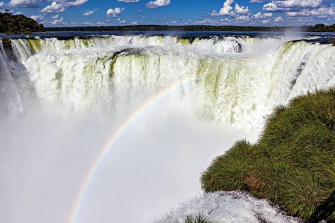 Impressive waterfall with rainbow and spraying spray under a blue sky, The Iguazu Falls between