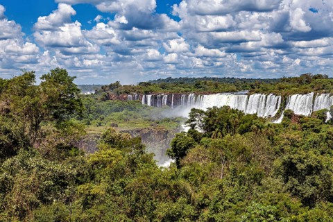 Dense vegetation frames impressive waterfalls under a cloudy sky, The Iguazu Falls between