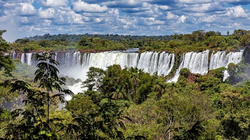 Grandiose waterfalls in a powerful river embedded in dense vegetation under a wide sky, The