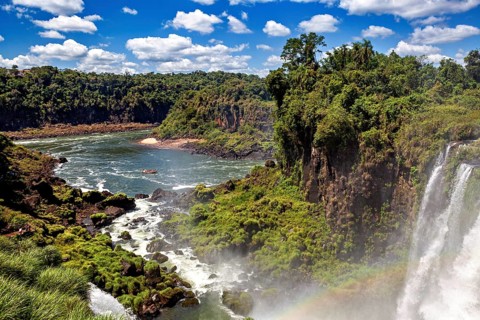 Extensive river landscape with waterfalls and lush riverside vegetation, boat on the water, The