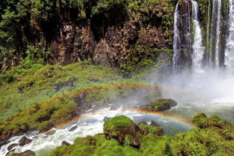 Rainbow over gushing water of a waterfall in green surroundings, The waterfalls of the Iguazu