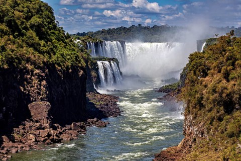 Majestic waterfalls with strong flow and spray, framed by lush vegetation, The Iguazu Falls between