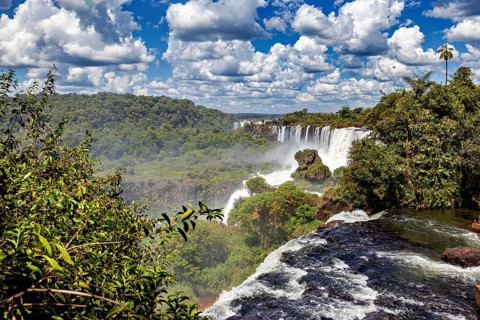 Rushing waterfall in dense vegetation under a vast sky, The Iguazu Falls between Argentina and