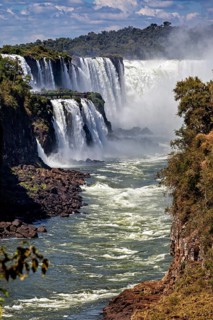 Impressive waterfalls with strong currents, surrounded by rocks and lush vegetation, The Iguazu