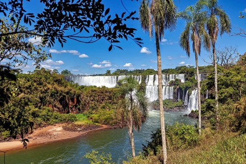 Picturesque views of waterfalls and palm trees offer a tropical panorama under a bright blue sky,