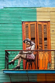 Female figure on a balcony in front of a striped façade, The colourful city and tango district of