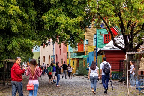 People walking on a colourful street with colourful houses and trees in an urban environment, The