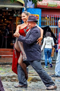 A couple happily dancing tango on a rain-soaked street in front of a café, The colourful city and
