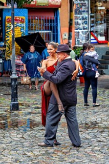 Tango couple in an intimate embrace dancing on a rainy street, surrounded by spectators, The
