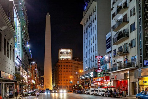 Night scene in a busy shopping street with the obelisk illuminated in the distance, The Great