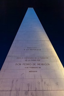 An illuminated obelisk with inscriptions in Buenos Aires at night against a deep blue sky, The