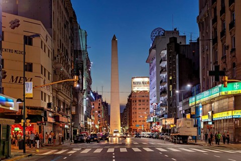 Twilight view of a busy city street, the obelisk illuminated by lights, The great obelisk in the