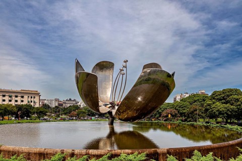 Metal flower sculpture near buildings with a cloudy sky in the background, The lotus blossom in