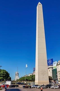 A tall obelisk under a clear sky in Buenos Aires in daylight, flanked by cars, The great obelisk in