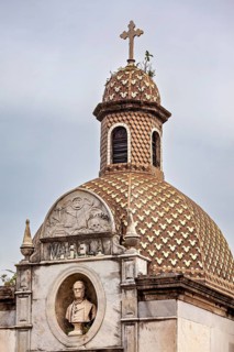 Historic structure with decorative dome, cross and a bust in an ornate relief, La Recoleta cemetery