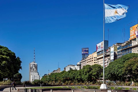 Argentinian flag flies over an urban scenery with buildings and blue sky, The skyline of the city