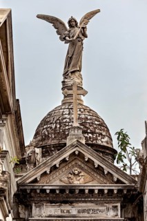 Angel sculpture on decorated dome above a historic building with Gothic design, La Recoleta