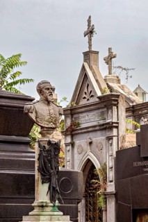 Monumental bust of a man in a cemetery, surrounded by historic tombs, La Recoleta Cemetery in