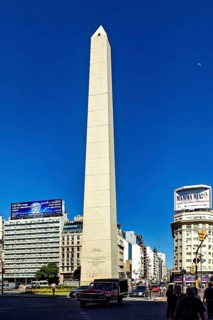 An obelisk in sunny weather in a busy city centre with traffic in the foreground, The large obelisk