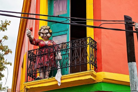Sculpture of a child with a balloon on a balcony in a colourful house, The colourful city and tango