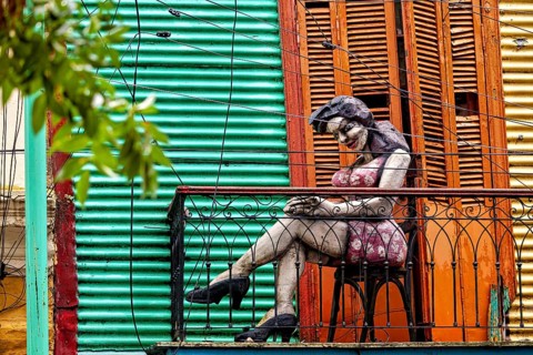 Sculpture of a woman on a decorative balcony with a coloured wall, The colourful city and tango