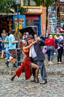 A couple performs impressive tango poses on a rain-soaked street with spectators, The colourful