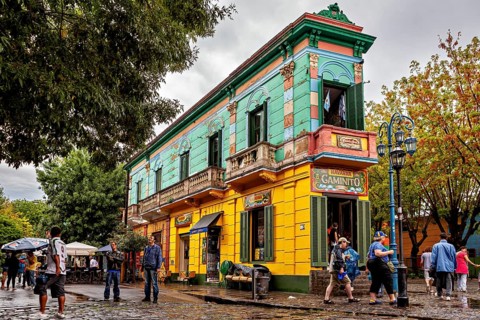A colourful historic building with cafés attracts people on a cobbled street, The colourful city