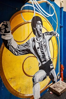 Mural of a cheering football player on a yellow and blue background, The football stadium of La