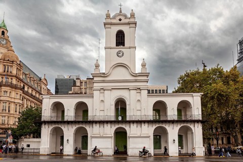 An old colonial style building with clock tower under a cloudy sky in the city, Historic buildings