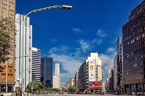 A busy city street with modern skyscrapers and heavy traffic under a blue sky, The city of Buenos