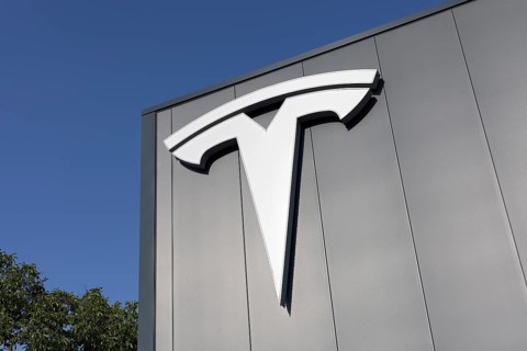 Tesla, logo on modern workshop building, figurative mark without lettering, US car manufacturer for