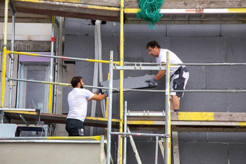 Construction workers insulate a house facade