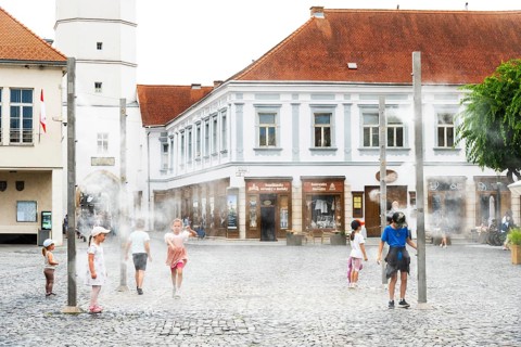 Water mist system in the city centre of Trencin, children use the refreshment in the summer heat,