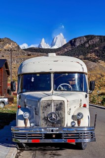 A vintage bus in front of a snow-covered mountain landscape, taken from the front view on a road, A