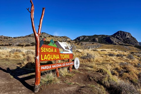 Signpost in the nature park pointing to a hiking trail under a clear blue sky, The Perito Moreno