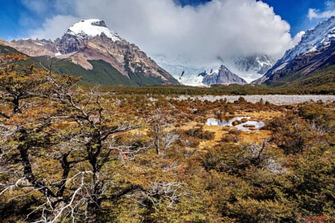 Snowy mountain scenery with wild foreland, clouds and a small pond in an autumnal landscape, The