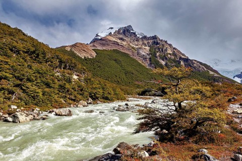 River flows through mountainous landscape with cloudy sky, The landscape of Patagonia in Argentina