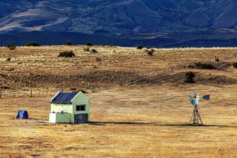 Abandoned small building with windmill in a dry, expansive landscape, The Patagonian landscape near