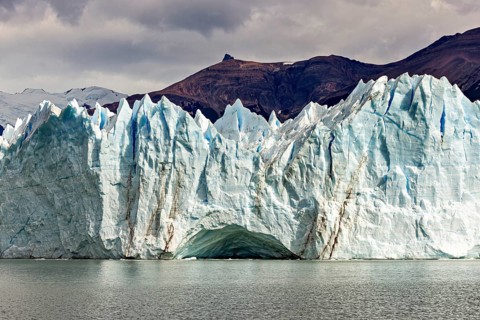 Impressive ice wall of a glacier under a cloudy sky near a mountain, The glacier of Perito Moreno