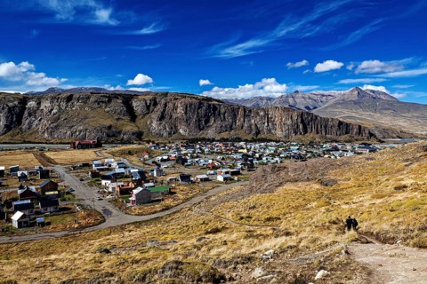 Small village in a barren landscape with high cliffs and blue skies, the village of El Chalten in