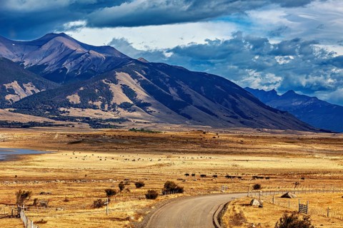 Wide plains with a winding road and a majestic mountain range in the background, the Patagonian