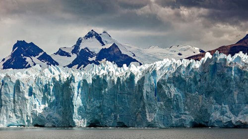 Mighty glacier landscape against a dark sky and snow-capped mountains in the background, The Perito