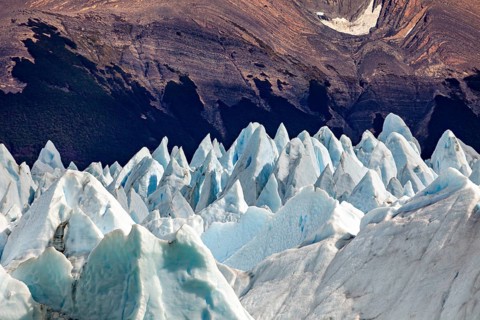 Pointed ice formations in front of a dark mountain landscape with an impressive natural backdrop,