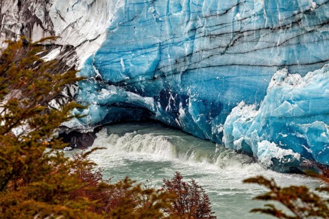 Flowing water under an impressive blue glacier wall, The Perito Moreno glacier in Argentina