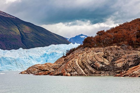 Frozen glacier water meanders between rocks and colourful forests, The Perito Moreno glacier in