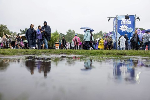 Festival-goers reflected in a puddle at the Lollapalooza Festival in the Olympic Stadium and on the
