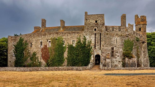 View of a stone castle with ivy and clouds in the sky, Pirou Castle in Normandy, France