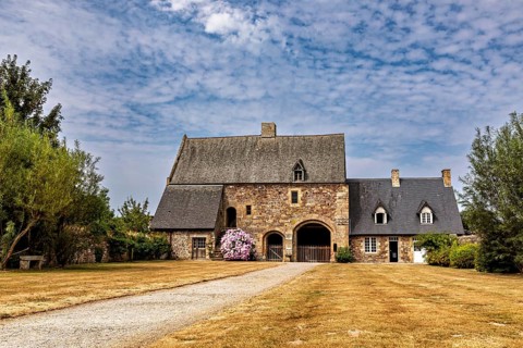 An old stone house with a gravelled path and a blue sky, surrounded by manicured lawns, The Abbey