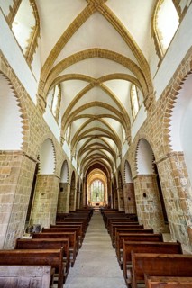 Interior view of a Gothic church with impressive arches and wooden rows of seats, The Abbey de La